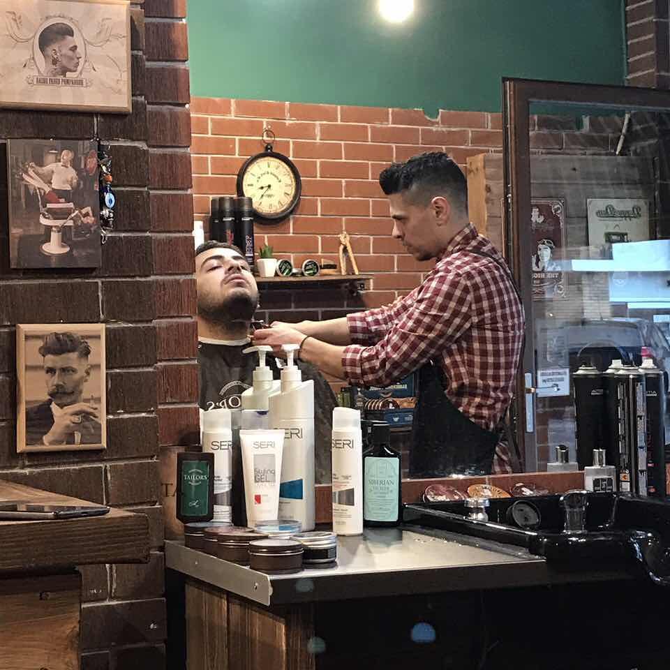 Ο τοίχος του Andrew’s Barber House: κάδρα, ξύλινη πλακέτα και το ρολόι πάνω από το τούβλο